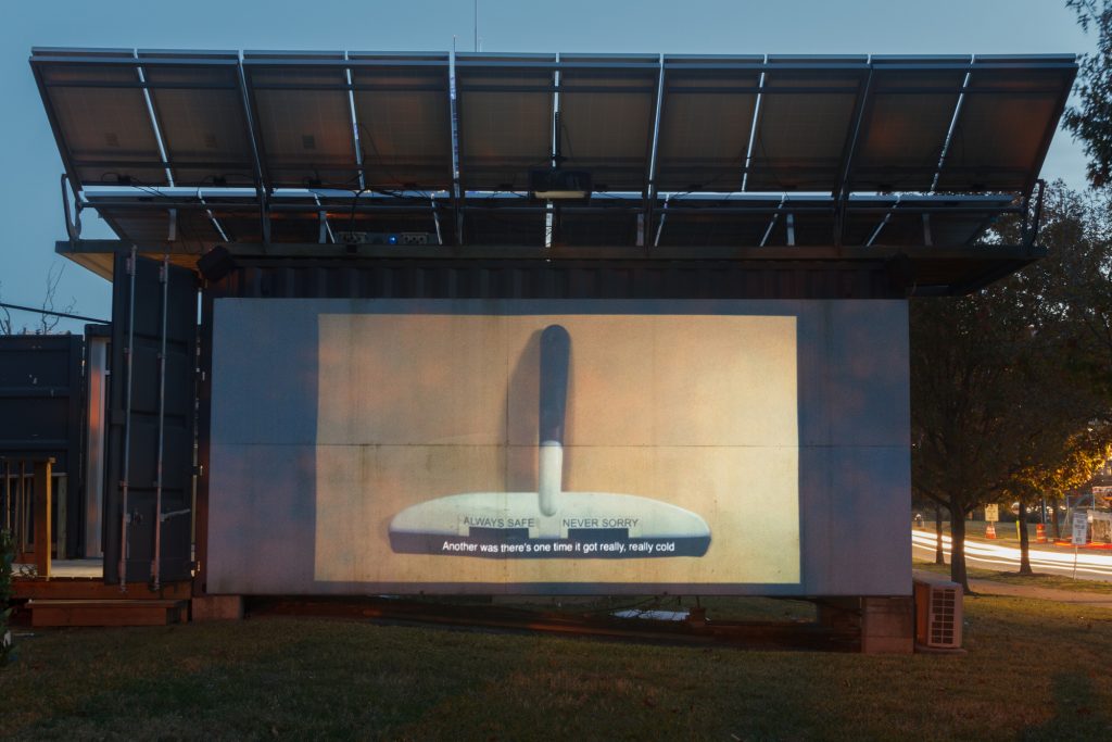 Photo of video projected on building showing squeegee and text subtitles